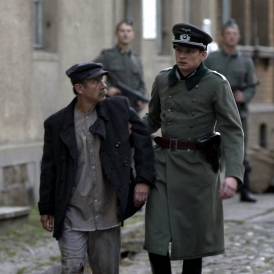 Wilm Hosenfeld in Militärkleidung führt einen Mann in Arbeitskleidung weg. (Foto: SWR – Screenshot aus der Sendung)