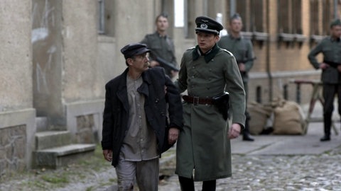 Wilm Hosenfeld in Militärkleidung führt einen Mann in Arbeitskleidung weg.