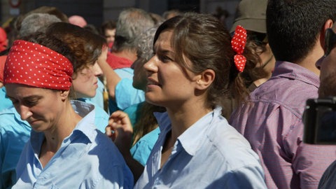 Viele Personen stehen auf der Straße, einige tragen etwas rotes mit weißen Punkten