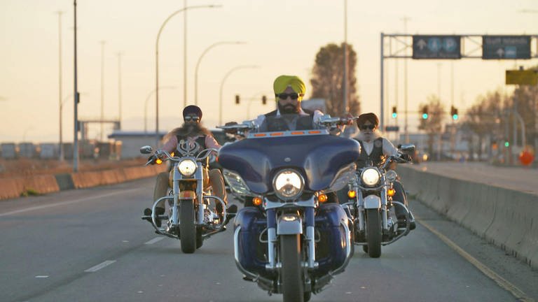 Drei Männer fahren auf einem Highway in Richtung der Kamera Motorrad