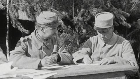Es sind Soldaten in Uniform beim Schreiben von Briefen zu sehen.
