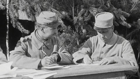 Es sind Soldaten in Uniform beim Schreiben von Briefen zu sehen.