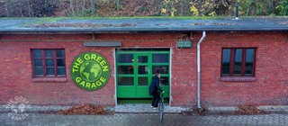 Backsteingarage, an der links daneben ein Schild mit der Aufschgrift "The Green Garage" hängt