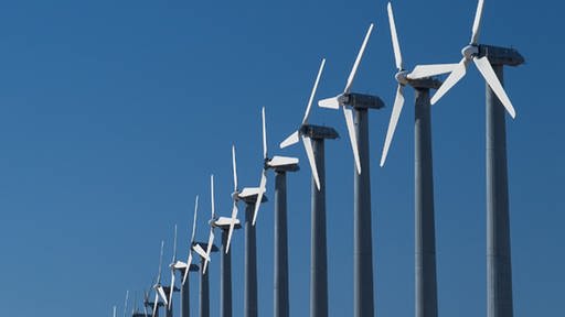 Mehrere Windturbinen stehen in einer Reihe. (Foto: Shutterstock)