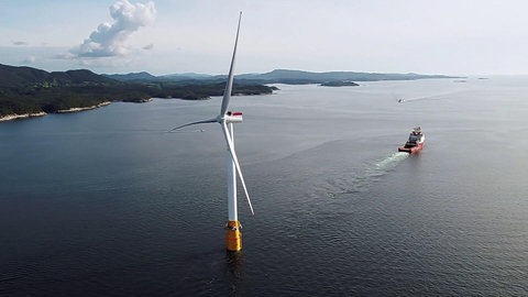 Schiff hat Windkraftanlage im Schlepptau.