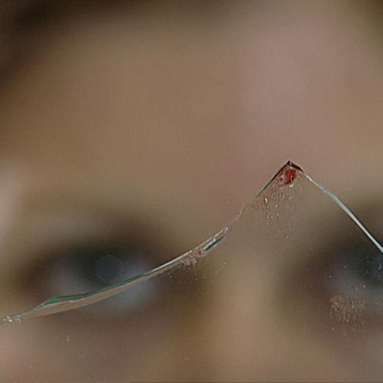 Frau schaut auf Glasscherbe mit Blutspur am Rand. (Foto: SWR – Screenshot aus der Sendung)