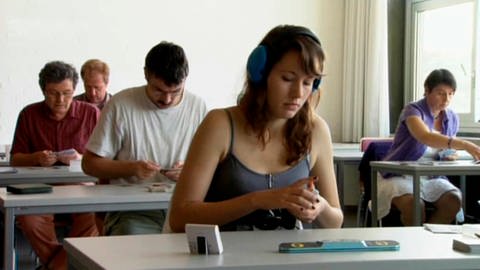 Männer und Frauen an Tischen schauen auf Spielkarten. (Foto: SWR – Screenshot aus der Sendung)