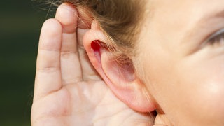 Kind hält sich die Hand hinter die Ohrmuschel: Hör gut zu beim Geräuschequiz von planet schule!