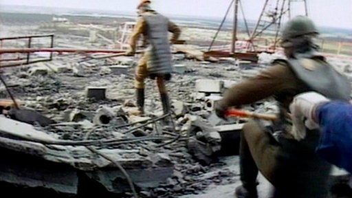 Männer mit Helmen und Bleischutz schaufeln Schutt.