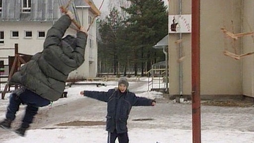 Zwei Kinder spielen auf einem Spielplatz.
