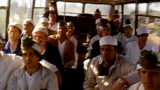 Männer in Arbeitskleidung in einem Bus.