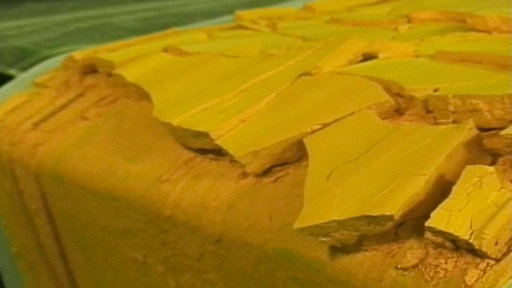 Gelbe Masse auf einem Fließband.