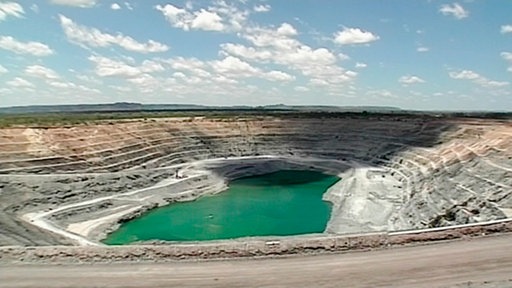 Uranabbau – terrassenförmig ausgebaggerte Erde mit See in der Mitte.