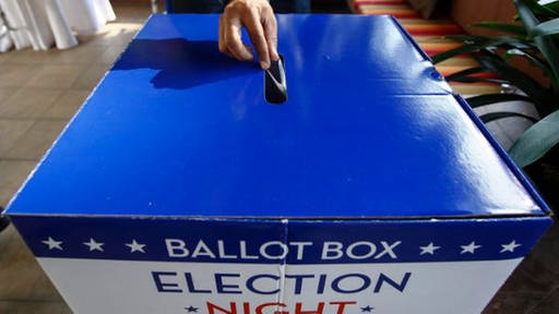Ein Wahlzettel wird in eine Box mit Sternen und Streifen darauf eingeworfen (Foto: WDR/dpa/Narendra Shrestha)