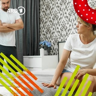 Ein Mann sieht misstrauisch auf seine Partnerin, die ernst auf dem Bett sitzt.