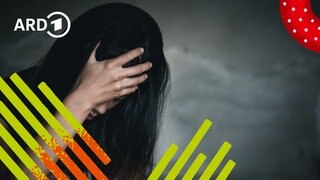 Ein Mensch sitzt am Tisch im Dunklen und verkrampft die Hände vor Angst