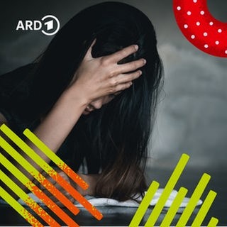 Ein Mensch sitzt am Tisch im Dunklen und verkrampft die Hände vor Angst