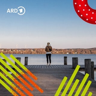 Eine Frau steht allein auf einem Steg am See und sieht in die Ferne.