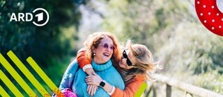 Zwei Freundinnen gehen Arm in Arm spazieren.