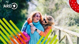 Zwei Freundinnen gehen Arm in Arm spazieren.