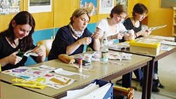 Mehrere Frauen basteln in einem Klassenzimmer.