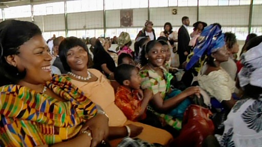 Festlich gekleidete Afrikaner in einer großen Halle.