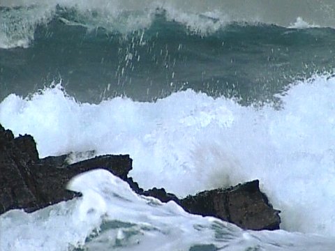 Starker Wellengang und Gischt an schwarzen Felsen [Klick auf das Bild, schließt das Fenster]