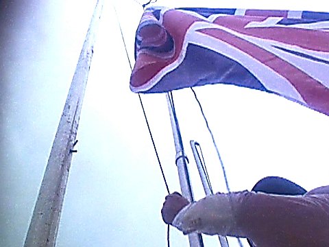 Ein Mann hisst eine englische Flagge [Klick auf das Bild, schließt das Fenster]