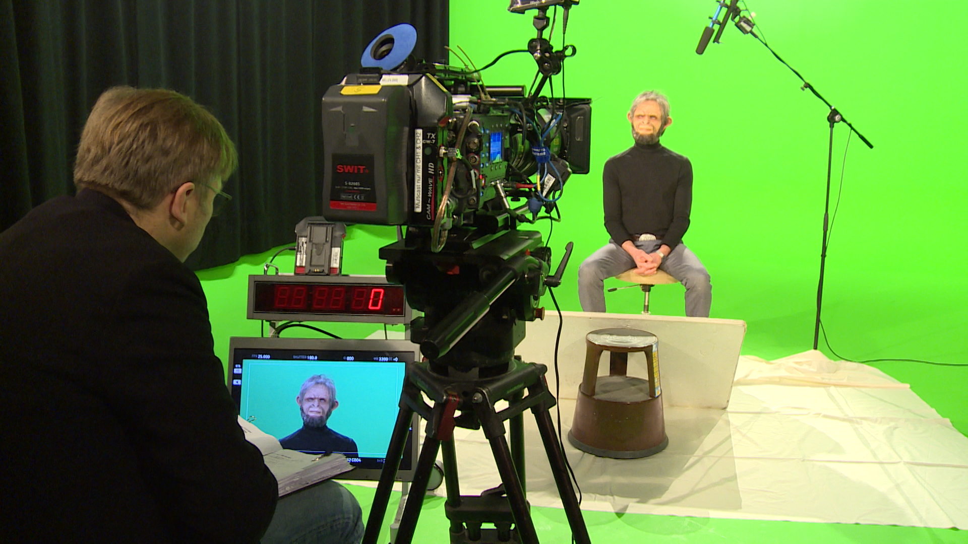 Regisseur und Affendarsteller vor grünem Hintergrund im Dialog