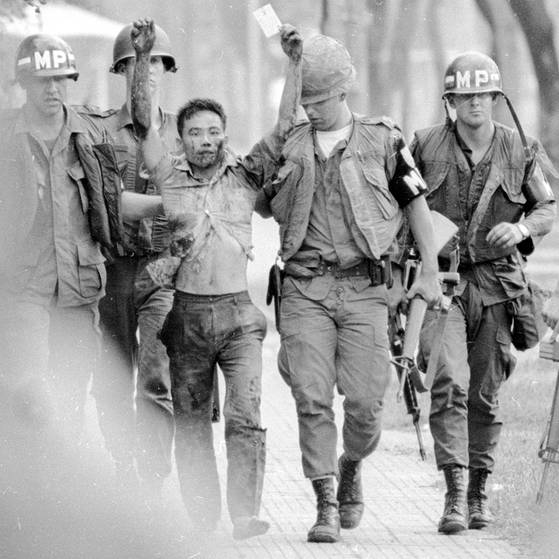 3 US-Soldaten in Uniform und mit Helmen führen einen Vietnamesen ab, der die Hände erhoben hat (Foto: imago images / United Archives International)
