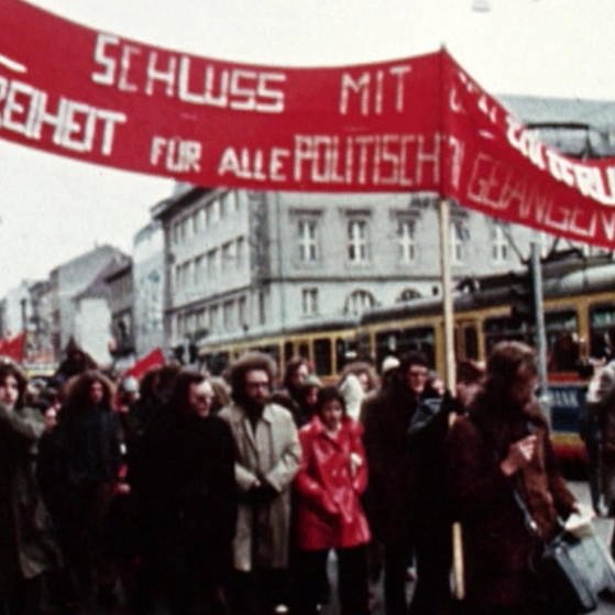 Demonstrationszug mit rotem Transparent (Foto: SWR - Screenshot aus der Sendung)