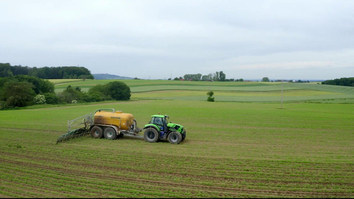 Traktor beim Ausbringen von Gülle auf Feld.