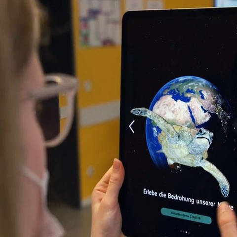 Eine Schülerin nutzt die WDR Klima-App auf einem Tablet, das eine Weltkugel und eine Schildkröte zeigt (Foto: WDR)