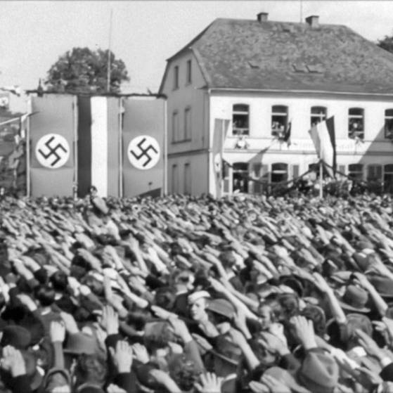 Schwarzweiß-Foto: Menschenmenge zeigt den Hitlergruß, im Hintergrund Fahnen mit Hakenkreuzen. (Foto: SWR – Screenshot aus der Sendung)