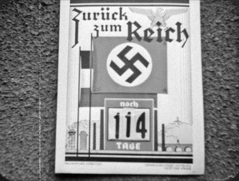 Plakat mit Hakenkreuz und Kalenderzählung 114 Tage „Zurück zum Reich“ (Foto: SWR – Screenshot aus der Sendung)