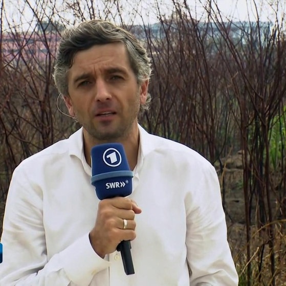 Matthias Ebert mit Mikrofon vor einer Hecke. (Foto: SWR – Screenshot aus der Sendung)