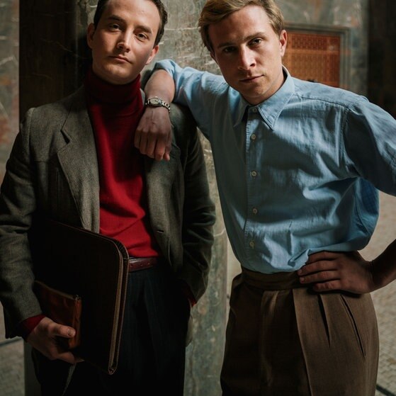 Spielszene: Hans (rechts) und Alexander stehen vor einer Säule in der Universität.