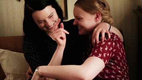 Spielszene: Sophie und Inge sitzen auf einem Bett und lachen.