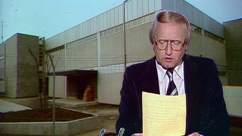 Tagesschausprecher; im Hintergrund die JVA Stuttgart-Stammheim