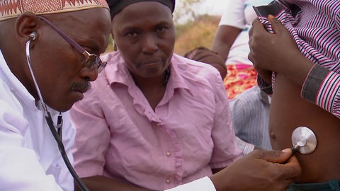 Ein Arzt hört den Bauch einer schwangeren Frau ab.