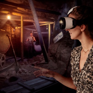 Frau mit VR-Brille schaut sich den Stollen eines Bergwerks an