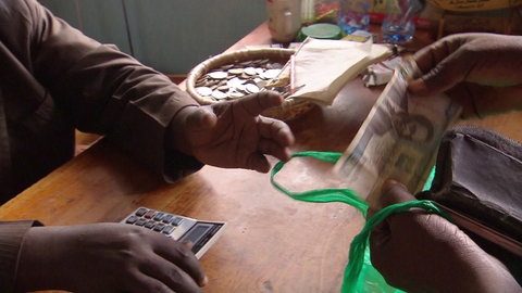 Ein Geldschein wechselt über eine Geschäftstheke seinen Besitzer