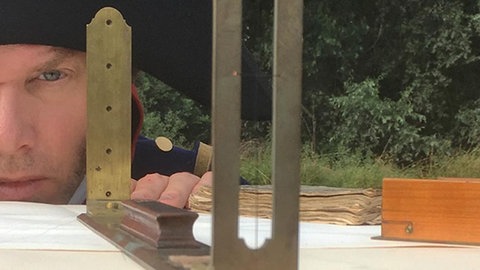 Nachgestellte Szene: Tulla benutzt ein Instrument um eine gerade Linie festzulegen.