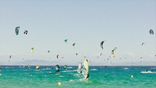 Surfer und Kitesurfer auf dem Meer