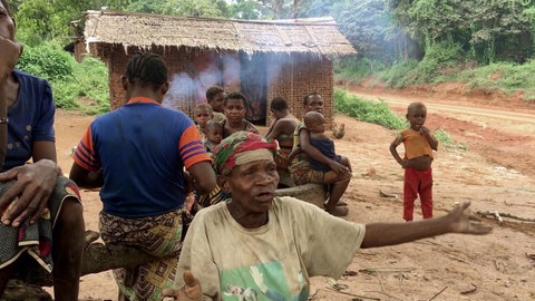 Dorf im Kongo : Menschen vor einer Hütte, im Vordergrund eine alte Frau.