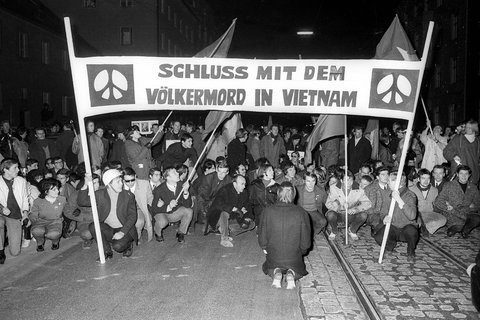Demonstranten im Sitzstreik; großes Transparent mit Aufschrift: „Schluss mit dem Völkermord in Vietnam“