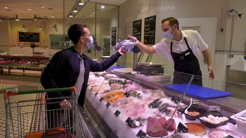 Käufer und Verkäufer an einer Fischtheke.