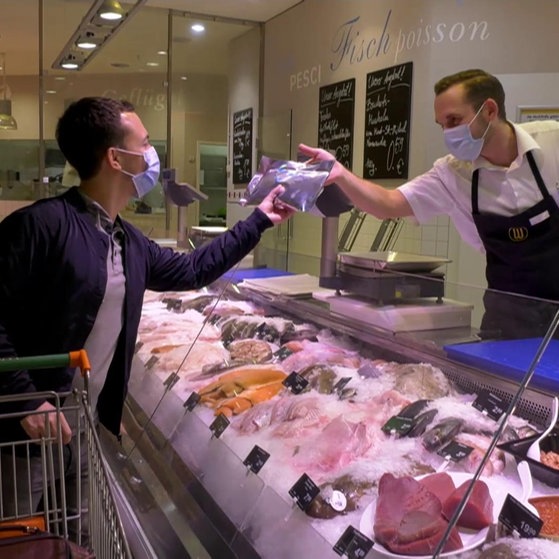 Käufer und Verkäufer an einer Fischtheke.