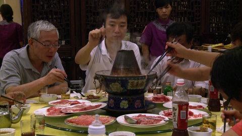 Mehrere Menschen sitzen um einen Esstisch.