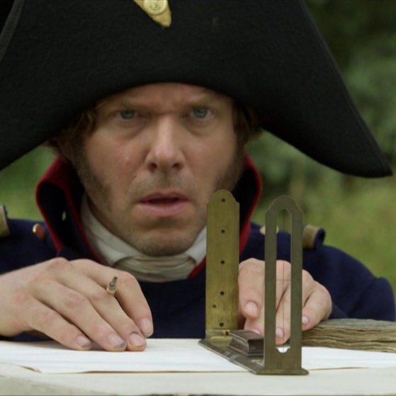 Nahaufnahme: Tulla-Darsteller mit Messinstrument auf Tisch.